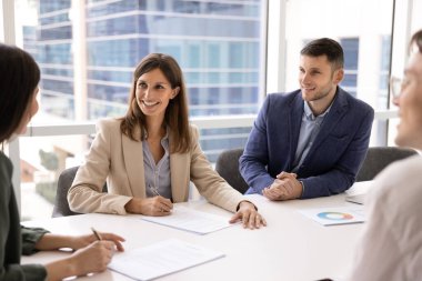 Mutlu bir şirket alıcısı ve satıcı sözleşmeyi imzalar, anlaşmayı imzalar, anlaşma yapar, büyük toplantı masasında konuşur, başlangıç projesi için yatırım pazarlığı yapar, gülümser.