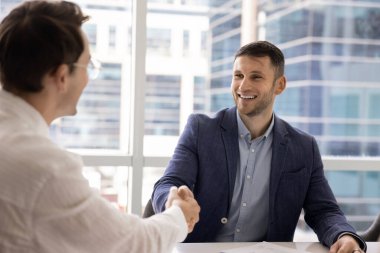 Neşeli başarılı bin yıllık iş adamı müzakere toplantısında erkek partnerle tokalaşıyor, gülümsüyor, gülüyor. İş dünyası lideri profesyonel eleman arıyor.