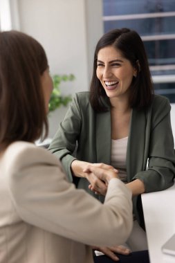 Mutlu, heyecanlı Latin iş danışmanı kadın, kadın iş arkadaşı, çalışan, konsültasyon toplantısından sonra müşteriyle el sıkışıyor, gülümsüyor, gülüyor, takım çalışmasına el sıkışarak teşekkür ediyor. Dikey çekim