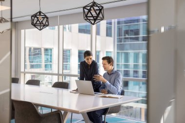 İşbirlikçi takım çalışması. İki farklı genç işadamı şirket çalışanları modern moda ofis yönetim kurulunda proje araştırmaları üzerine fikir paylaşımı yaparak evrak işlerini tartışıyor. Boşluğu kopyala