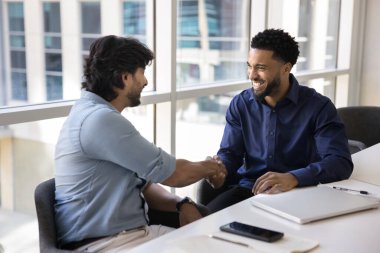 Başarılı bir ortaklık. İki mutlu dost canlısı iş adamı ofis masasında el sıkışıyor ve etkili bir işbirliğinden memnun kalıyorlar. Minnettar erkek stajyer, akıl hocasının yardımını takdir ediyor.