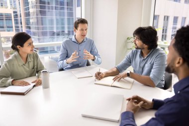 Fikir veriyor. Gen z erkek girişimcisinden esinlenerek ofis çalışanı yaratıcı ekip üyesi, proje geliştirme atölyesi konferansında çeşitli polietnik iş arkadaşları grubuna öngörü önerisi sunuyor