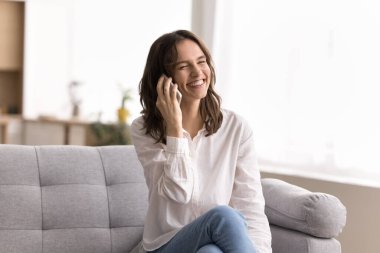 Neşeli telefon konuşması. Neşeli milenyum kadını oturma odasındaki yumuşak kanepeye uzanıp cep telefonuyla gülüyor, eğlenceli sohbetler ediyor haberleri tartışıyor sıcak evdeki dostça sohbet iletişiminin keyfini çıkarıyor.