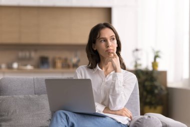 Fikir üretiyorlar. Düşünceli genç kadın rahat kanepeye otur kucağına not defterini koy ekrandan yana bak serbest proje projesine odaklan öğrenme zorluğu planına odaklan gelecekteki gezi için metin içeriği oluştur