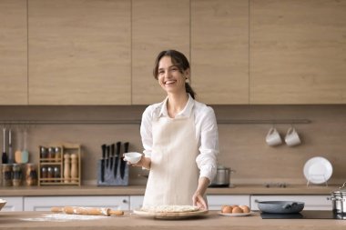 Yaşam tarzı aşçılık. Mutfak portresi neşe dolu genç kadın fırıncı tezgahın üstünde rulo hamurla poz veriyor kameraya bak ham pizzanın içeriğini aç video tarifi blogu için içerik oluştur