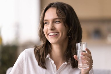 Sağlıklı yaşam tarzı ve su kaybı. Güzel, neşeli, genç bir kadının portresi temiz, durgun bir su bardağı tutuyor. Parlak bir gülümsemeyle, cilt bakımı, ferahlatıcı sıvı dengeyi teşvik ediyor.