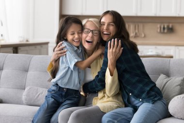 Sıcacık kucaklaşarak. Sevinçten havalara uçmuş yaşlı bayan mutlu bir şekilde gülüyor. Sevgi dolu, yetişkin bir kızın torununun sevgi dolu kucaklamalarıyla sıcak bir ev mutfağında sevgili çocukların minnettarlığı ile dokunuyor.