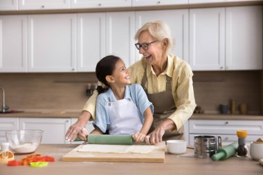 Nesiller pişirme ile birleşti. Mutlu yaşlı büyükanne kurabiyeleri ve neşeli küçük torun hamur işlerini bir araya getir. Birbirine toka atarak gülümse ve ev yapımı yemek pişirmenin keyfini paylaş.