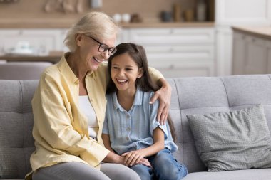 Aşkın sıcaklığı kucaklıyor. Sevecen, yaşlı bir büyükanne, küçük torununun omuzlarını kucaklıyor. Kanepede oturuyor. Şefkat ve şefkat desteği veriyor. Boşluğu kopyala