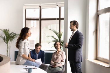 İşbirlikçi ruh. Çeşitli cinsiyet yaşlarındaki çok ırklı işçiler, gündelik toplantı için ofis salonunda toplandılar. Yaratıcı fikir alışverişi değerlendirme kağıtlarını gevşek sohbetlerde tartışacaklar.