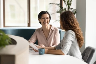 Müşteri danışmanlığı. Genç kadın profesyonel vergi danışmanı ipotek komisyoncusu iş ruhsat acentesi olgun bir kadınla tanıştı. Kontrat detaylarını modern ofiste açıklayın.