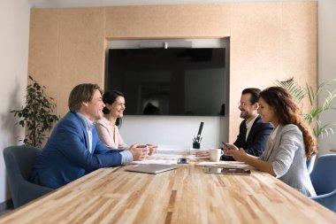 Dost canlısı hissedarlar tartışması. Çok uluslu gülümseyen iş ortakları çeşitli cinsiyet yaş grupları stratejik planlama yapan şirket yönetim kurulu masasında anlaşmaları tartışıyor.