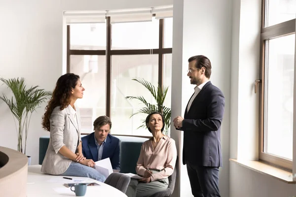 İşbirlikçi ruh. Çeşitli cinsiyet yaşlarındaki çok ırklı işçiler, gündelik toplantı için ofis salonunda toplandılar. Yaratıcı fikir alışverişi değerlendirme kağıtlarını gevşek sohbetlerde tartışacaklar.
