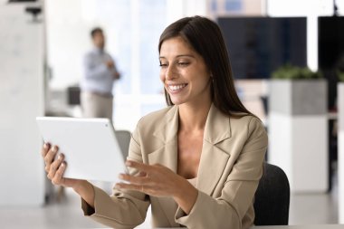 Mutlu, güzel, profesyonel İspanyol kadın tablet bilgisayardan online içeriği izliyor, iş molalarında sosyal medyada geziniyor, iş yerinde dijital cihaz kullanıyor, internet teknolojisinden keyif alıyor.