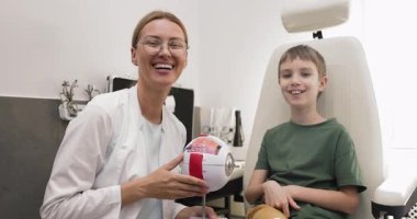 Modern oftalmoloji kliniğinde eğitim danışmanlığı sırasında kameraya poz veren anatomik göz modelini tutan gülümseyen kadın optometristin portresi. Görme kontrolü.