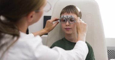 Göz hekimliği kliniğinde profesyonel göz muayenesi sırasında erkek yüzü üzerinde deney çerçevesini ayarlayan optometriste yakın çekim. Erken safhada miyop, hiperopi veya astigmat teşhisi, vizyon hizmetleri kontrol