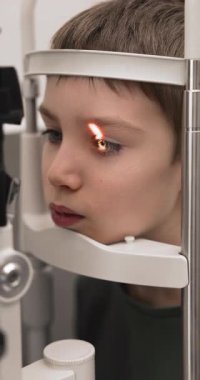 Optometri merkezinde kesik lamba göz muayenesi yapılan küçük şirin çocuğa yakın çekim. Profesyonel klinikte miyop veya astigmat erken teşhisi için görme ve kornea sağlığının ayrıntılı kontrolü