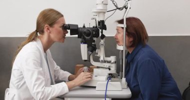 Modern optik klinikteki yaşlı kadınların gözlerini incelemek için kesik lamba biyomikroskobu kullanan oftalmolog, kornea, retina ve lens sağlığını kontrol etmek için teşhis prosedürünü geçen hasta. Vizyon değerlendirmesi