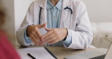 Beyaz önlüklü ve steteskoplu kadın doktorların klinikteki masasında oturup, tıbbi danışmanlık sırasında hastalarla konuştuklarını. Profesyonellik, berraklık, sağlık hizmetleri iletişimine güven