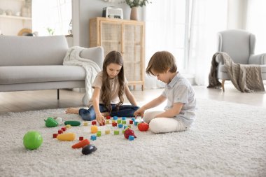 Yaratıcı aktivite. Erken okul çağındaki meraklı küçük çocuklar, abla küçük kardeş, oyuncak sebzelerle sessiz bir oyun oynuyor. Oturma odasındaki sıcak zeminlerde konuşuyorlar. Birlikte fantezi kuruyorlar.