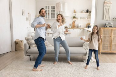 Spontane aile eğlencesi. Sevinçten havalara uçan yeni ev sahipleri kiracılar mutlu aile ve küçük 7 'li kızlar taşınma günü kredinin ödenmesini kutlarken parlak, rahat stüdyo dairesinde dans ediyorlar.