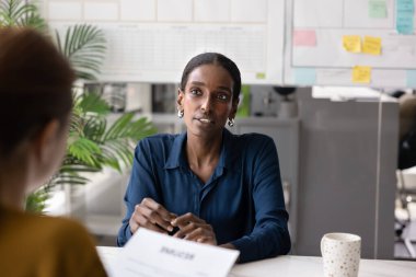 Ciddi bir Afrikalı genç kadın mülakatta işe alım yapan bayanla konuşuyor, işverenin sorularını yanıtlıyor. Kadın iş danışmanı müşteriye anlaşma şartlarını açıklıyor
