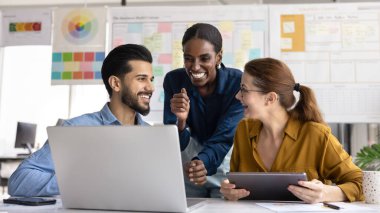 Çevrimiçi proje sunumunu tartışan, iş masasında buluşan, konuşan, gülen, ofis masasında profesyonel pazarlama içeriğini izleyen çok ırklı iş adamlarından oluşan mutlu bir ekip.