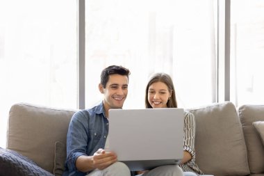 Evdeki rahat koltukta dinlenen, dizüstü bilgisayarın keyfini çıkaran, modern oturma odasında dertsiz tasasız vakit geçiren bir çift. E-servis alışverişi, pazar platformu üzerinden mal siparişi