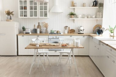 Hafta sonu pastanesi hazırlığı. Işığın rahat, şık iç mekanı. İnsansız, geniş donanımlı, modern ev mutfağı. Ev yapımı pişirme malzemeleriyle dolu bir masa. Aile yemekleri için klasik aletler.