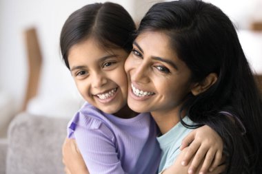 Güzel, mutlu Hintli bir kadının, 5 yaşındaki anaokulu kızına sarılıp gülen, sıcaklığın ve şefkatin tadını çıkaran güzel yüzleri. Anne ve çocuk arasındaki bağlılık ve koşulsuz sevgi