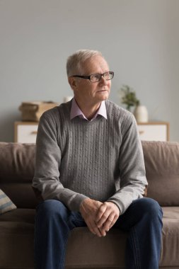 Derin düşünceler içinde. Ciddi nostaljik bir portre. Gözlüklü yaşlı adam emekliliğinde evde tek başına oturuyor. Koltukta oturuyor.