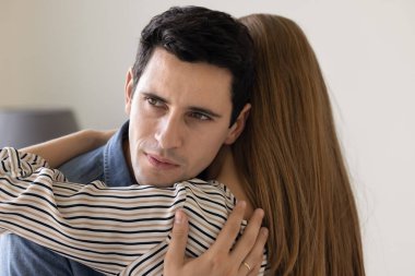 Duygusal gerilim ve endişeli bir ifadeyle bakışlarını kaçırarak kadını kucaklayan genç bir adam. İlişkiye olan güvensizlik, güvensizlik ve şüphe, ihaneti gizleme, ilişkilerdeki güvenin karmaşıklığı