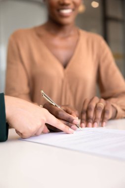 Menajer, satıcı, yasal uzman, mutlu Afrika kökenli Amerikalı kadın müşteriler için imzalanacak yeri işaret ediyor, alıcı sözleşmesi, anlaşma. Kolların dikey yakın çekimi