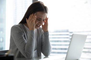 Bilgisayar işinden dolayı zihinsel yorgunluk. Stresli genç iş kadını öğrenci çalışanı iş yerinde baş ağrısı çekiyor. Aşırı bilgi yüklenmesinden yorulan not defteriyle fazla uğraşan tapınakları ovuyor.