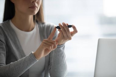 Rutin sağlık kontrolü. Yakın mesafeden doğranmış genç bayan dijital glukometreyle parmak ucunda oturuyor. Diyabet yönetimi konsepti için günlük kan şekeri izleme teknolojisi. Boşluğu kopyala