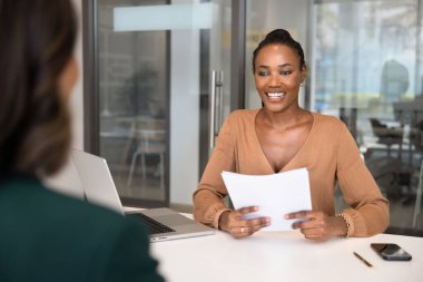 İş görüşmesinde adayla konuşan, özgeçmişi tartışan, iş becerileri, deneyim ve beklentiler hakkında sorular soran mutlu Afrikalı profesyonel kadın. İki farklı iş kadını buluşuyor.