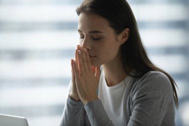 Çözüm için dua ediyorum. Kapalı gözlü serbest çalışan genç bayan öğrenci portresi. El ele tutuşup el ele tutuşun. Gizli dilekler fısıldayın.