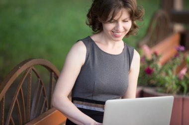 Young woman working on laptop outside