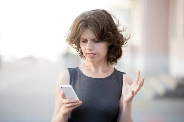 Young business woman irritated with her phone — Stockfoto