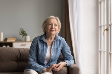 Düşünme ve iç huzur zamanı. Portre sakin, düşünceli, yaşlı kadın, gri saçlı, şık kot elbiseli, rahat koltukta rahatla. Rüya gibi bir ruh halinde kenara bak. Gençlik günlerini hatırla.