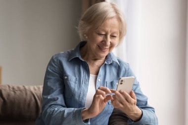 Modern teknoloji emeklisi. Mutlu gülümseyen stil sahibi yaşlı kadın emekliler, internet sörfü sosyal ağlarında flört uygulamalarında cep telefonlarını kullanmaktan keyif alırlar.