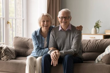 Mutlu emeklilikler. Portre seven yaşlı evli çift rahat koltukta dinleniyor. Kameraya bak. Neşeli yaşlı eş, sımsıkı sarıl kocana. Aile hayatında derin bir bağ kurma sevinci göster.