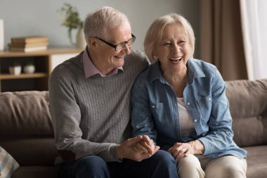 Aşkın altın yılları. Sıcak romantik portre, neşeli, sevgi dolu yaşlı çift, karı koca, rahat koltukta sarılıyor, el ele tutuşuyor, gülüyor, aile hikayelerini anımsıyor, karşılıklı derin duygusal bağlar kuruyoruz.