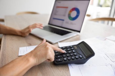 Hesap makinesi ve dizüstü bilgisayarla çalışan, grafikleri gösteren, kağıt ve makbuzlarla masaya oturan, bütçe, muhasebe, finans ve para yönetimini temsil eden tanınmamış kadınların yakın çekimleri