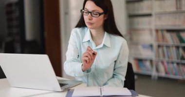 Modern işyerindeki masaüstü bilgisayarını kullanarak e-öğrenirken ya da çevrimiçi çalışırken kağıt organizatörüyle notlar ya da fikirler yazan iş kadını. Ofis iş akışı, görev planlaması, bilgi analizi, verimlilik