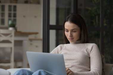 Dizüstü bilgisayar kullanan, bilgisayar başında çalışan, evdeki kanepede dinlenen ciddi bir serbest çalışan kadın. İnternet öğrencisi Webinar öğrenirken izliyor. Uzaktan çalışan, profesyonel e-posta mektubu okuyan.,