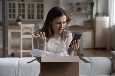 Sinirli müşteri internet mağazasından yanlış paket alıyor, çevrimiçi uygulamaları kontrol ediyor, cep telefonundan internet hizmetlerini kontrol ediyor. Sinirli kadın, müşteri, alışveriş kutusunu açan akıllı telefon kullanan...