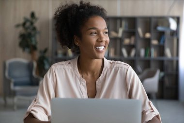 Mutlu Afro-Amerikalı öğrenci dizüstü bilgisayar kullanıyor, evden ders çalışıyor, Webinar öğrenirken pencereye bakıyor, iş molasında iyi bir gelecek eğitimi düşünüyor, gülümsüyor. Kafasından vur.