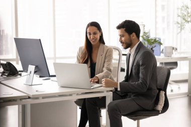 Genç profesyonel kadın, erkek müşterisiyle toplantı yapar, bilgi verir, sözleşme detaylarını açıklar, online teklif veya modern çalışma ofisindeki masada oturan dizüstü bilgisayarın sunumunu gösterir