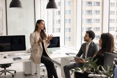 Kendine güvenen kadın proje yöneticisi sunum yapıyor, çözümü açıklıyor, yeni strateji, modern iş ortaklığında toplantı veya beyin fırtınası sırasında takım arkadaşlarıyla proje planını tartışıyor